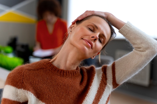 Foto gratuita mujer en la oficina estirándose durante un día de trabajo