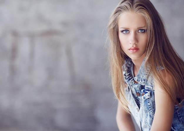 Mujer de ojos azules con pelo largo y rubio con chaqueta vaquera.