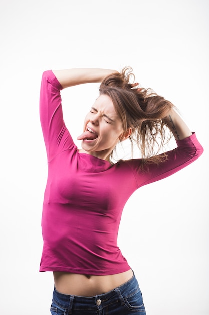 Mujer con los ojos cerrados sacando la lengua con las manos en la cabeza