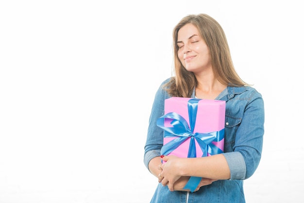 Mujer con los ojos cerrados sosteniendo el regalo de cumpleaños en el fondo blanco