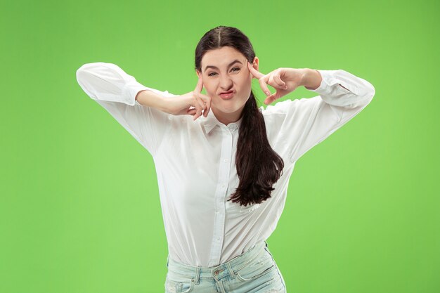 mujer de ojos entrecerrados con expresión extraña. Hermoso retrato femenino de medio cuerpo aislado sobre fondo verde de estudio.