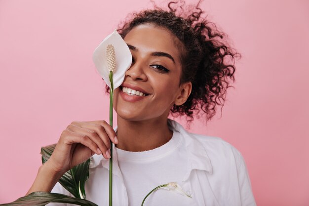 Mujer de ojos marrones cubre su rostro con una gran flor