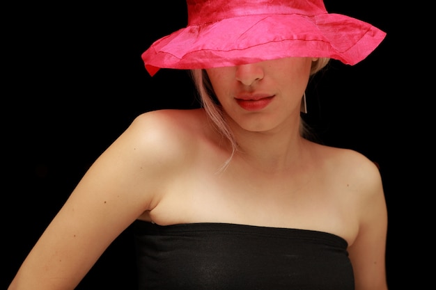 Foto gratuita mujer con los ojos tapados por un sombrero con fondo negro