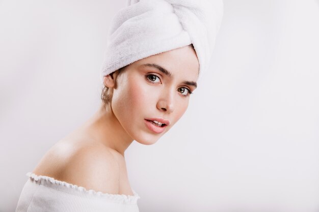 Mujer de ojos verdes. Señora de piel sana posando en toalla después de la ducha.