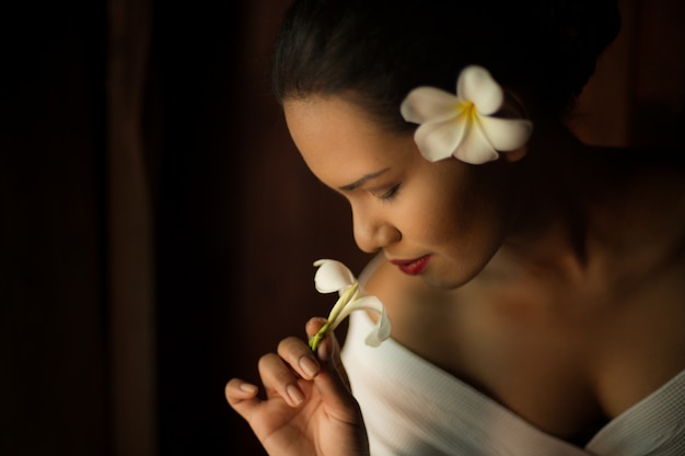 Mujer oliendo una flor blanca de cerca