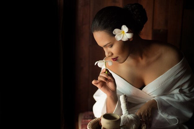 Mujer oliendo una flor blanca