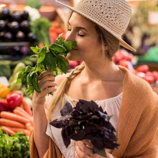 Foto gratuita mujer oliendo hojas naturales en el mercado