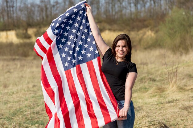 Mujer ondeando la bandera de Estados Unidos fuera durante el día de la independencia