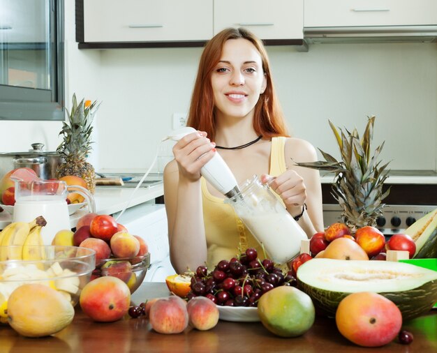 Mujer ordinaria cocinando milkshake con frutas