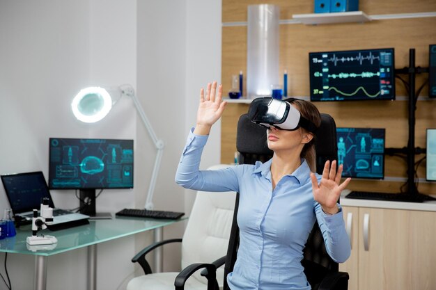 Mujer paciente analizando su cerebro en realidad virtual. Laboratorio futurista y moderno