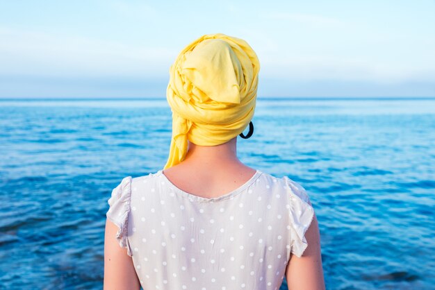 Mujer con un pañuelo amarillo disfrutando de la vista al mar