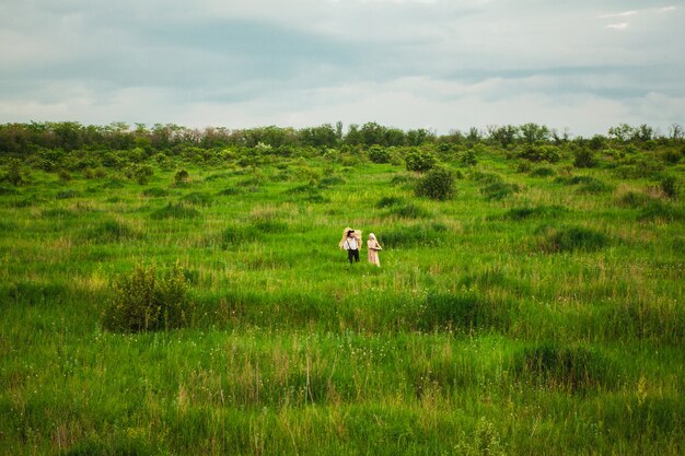 mujer en pañuelo y hombre caminando en la pradera