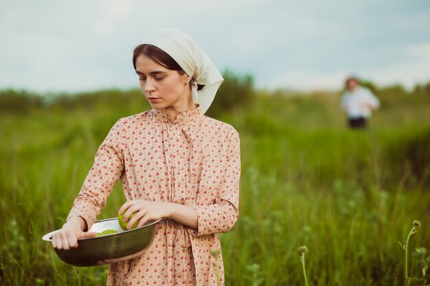 La mujer del pañuelo con manzanas contra el prado verde
