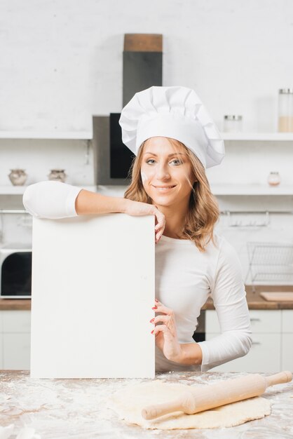 Mujer con papel en blanco en cocina