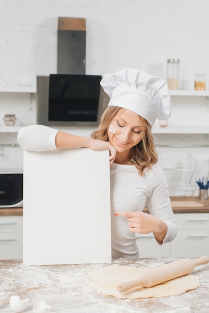 Mujer con papel en blanco en cocina