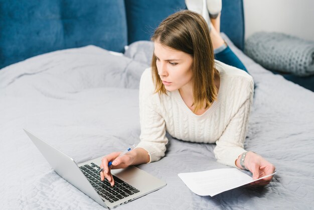 Mujer con papeles usando laptop