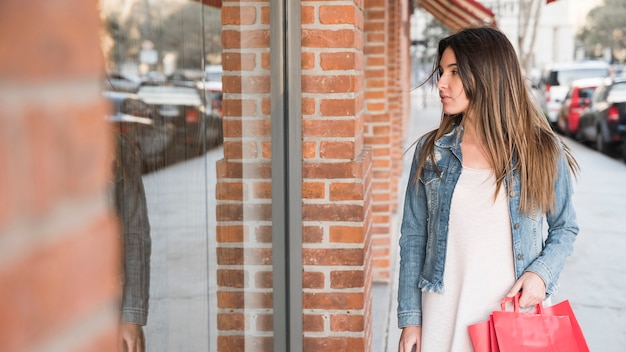 Mujer con paquetes de compras mirando escaparates