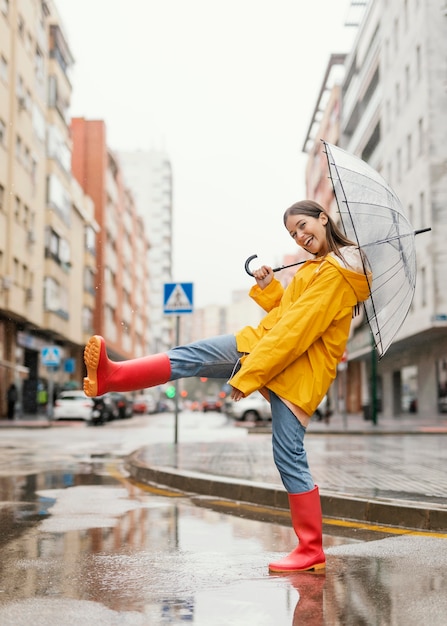 Mujer con paraguas de pie bajo la lluvia vista frontal