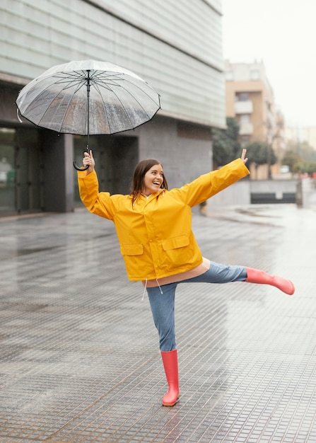 Mujer con paraguas de pie bajo la lluvia vista frontal