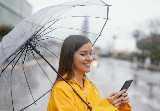 Mujer con paraguas usando el teléfono móvil