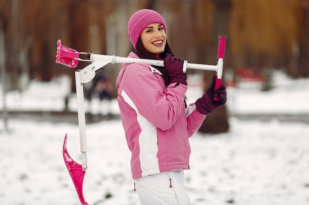 Foto gratuita mujer en un parque de invierno. dama en traje deportivo rosa. mujer con moto de nieve.