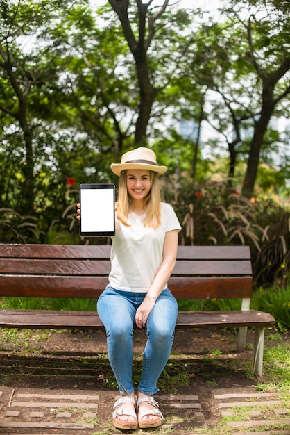 Foto gratuita mujer en parque mostrando tableta con pantalla en blanco