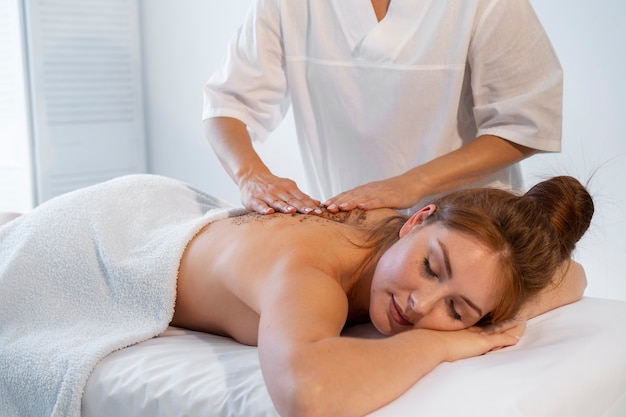 Mujer pasando tiempo en el spa y recibiendo un masaje de exfoliación