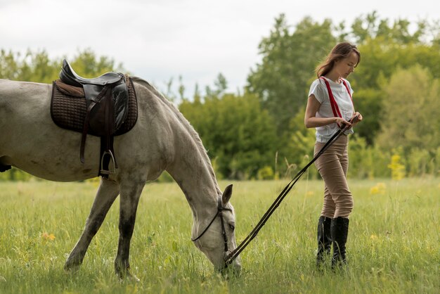 Mujer paseando con un caballo en el campo