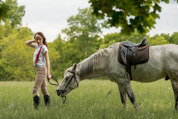 Mujer paseando con un caballo en el campo
