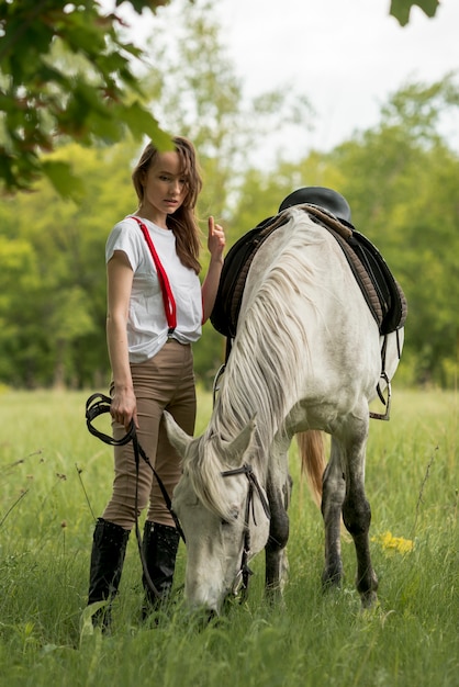 Foto gratuita mujer paseando con un caballo en el campo