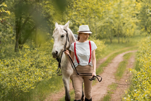 Foto gratuita mujer paseando con un caballo en el campo