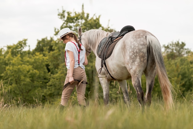 Mujer paseando con un caballo en el campo