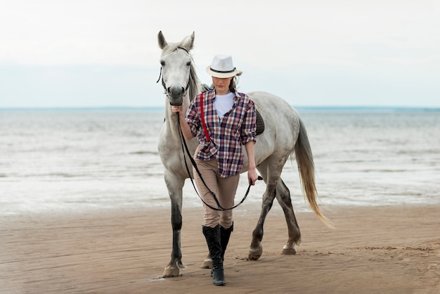 Foto gratuita mujer paseando con un caballo por la playa