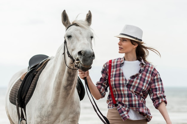 Foto gratuita mujer paseando con un caballo por la playa