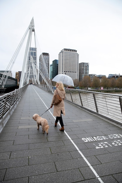 Foto gratuita mujer paseando a su perro por un puente mientras llueve