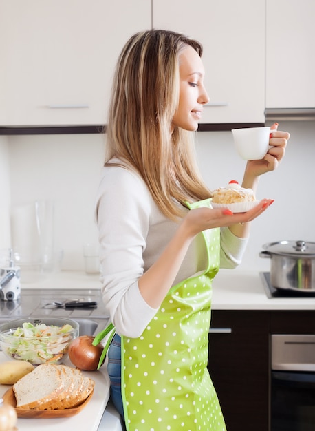 Mujer con pasteles y té en la cocina