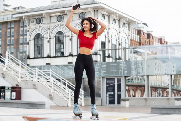 Mujer con patines escuchando música y usando su teléfono inteligente al aire libre