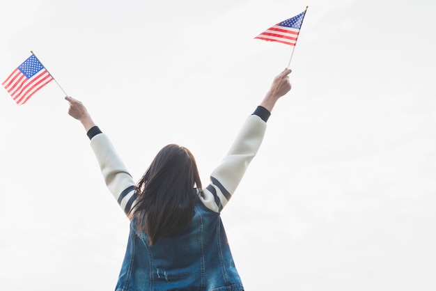 Mujer patriota con banderas en las manos extendidas.