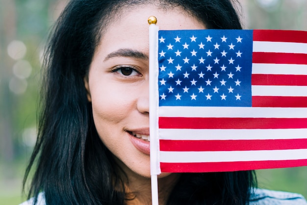 Mujer patriótica que cubre la cara con la bandera de Estados Unidos