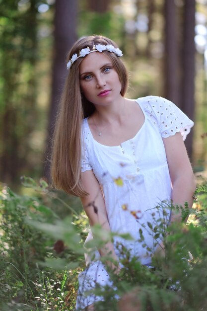 Mujer pecosa con círculo de flores en su retrato de cabeza en el bosque de otoño a la luz del día.