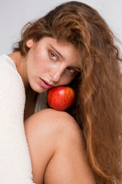 Mujer pecosa posando con manzana roja