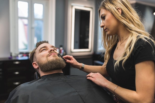 Mujer peinando la barba del cliente