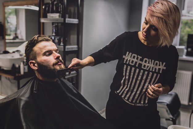 Mujer peinándose barba de hombre guapo