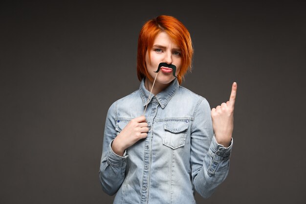 Mujer pelirroja con bigote falso haciendo muecas