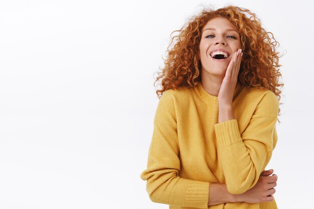 mujer pelirroja con cabello rizado, vistiendo un suéter amarillo, riendo arrogante y complacido