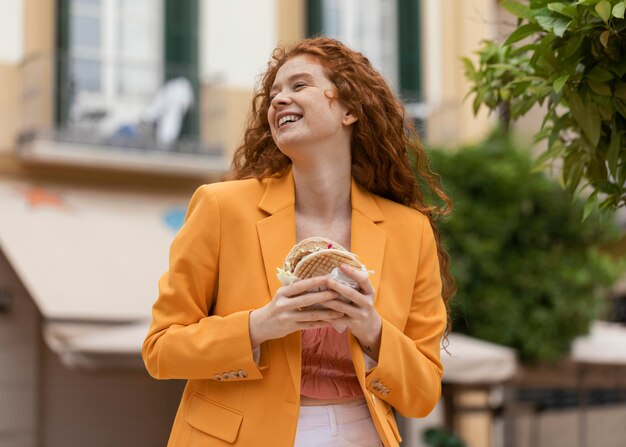 Mujer pelirroja comiendo algo de comida en la calle