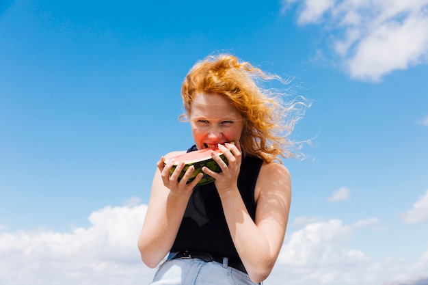 Foto gratuita mujer pelirroja comiendo rebanada de sandia