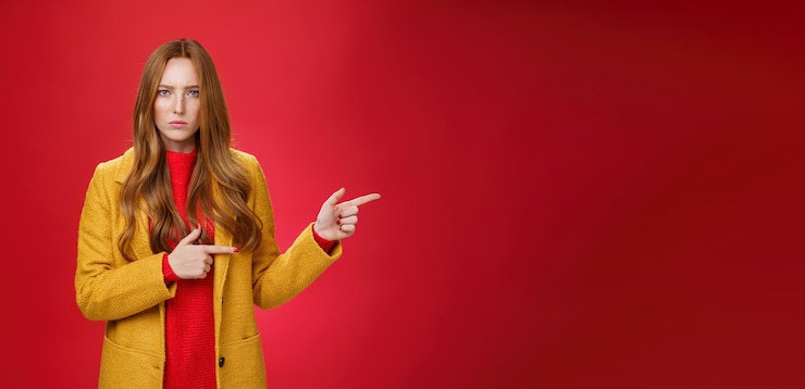 Foto gratuito mujer pelirroja decepcionada enojada y ofendida con abrigo amarillo frunciendo el ceño mirando estricta y seria a