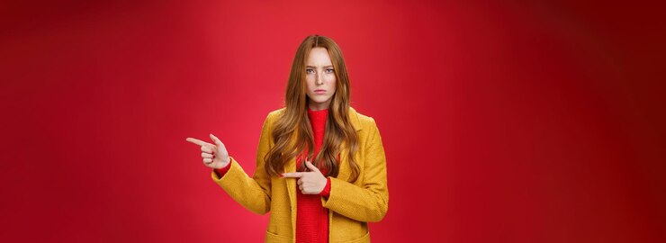 Foto gratuito mujer pelirroja decepcionada enojada y ofendida con abrigo amarillo frunciendo el ceño mirando estricta y seria a