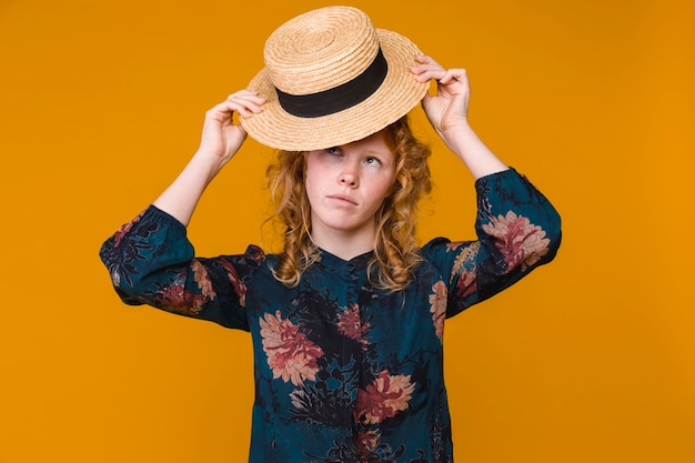 Mujer pelirroja joven que pone en el sombrero beige